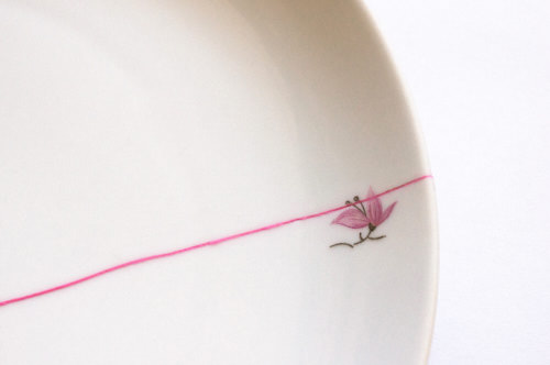 Close-up of a white plate with a flower motif and a visible crack filled with a pink substance